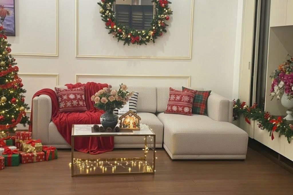 Phòng khách ấm cúng với sofa chữ L, bàn trà và không gian trang trí Giáng Sinh sang trọng gồm cây thông, vòng nguyệt quế và phụ kiện Noel