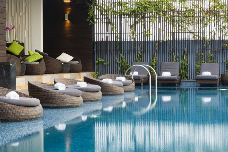 Giường tắm mây nhựa kèm đệm xám, bố trí sang trọng tại khu nghỉ dưỡng ven hồ bơi.