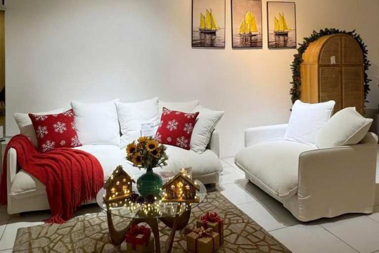 Không gian phòng khách thanh lịch với sofa trắng, gối tựa đỏ nổi bật cùng trang trí Giáng Sinh ấm áp, tạo điểm nhấn tinh tế cho mùa lễ hội.