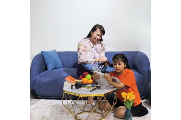 Gia đình sinh hoạt trong phòng khách với sofa băng bọc vải màu xanh, không gian ấm cúng và thân thiện – nội thất hướng đến trải nghiệm sống.