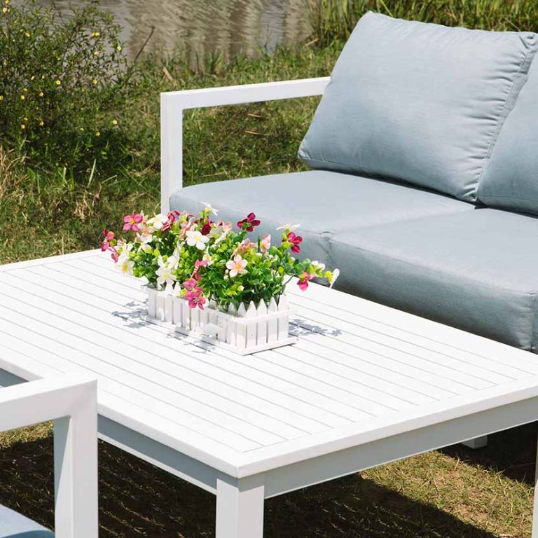 Cận cảnh bàn sofa ngoài trời Paxi màu trắng, thiết kế nan thoáng, kết hợp ghế đệm xám trong không gian sân vườn.